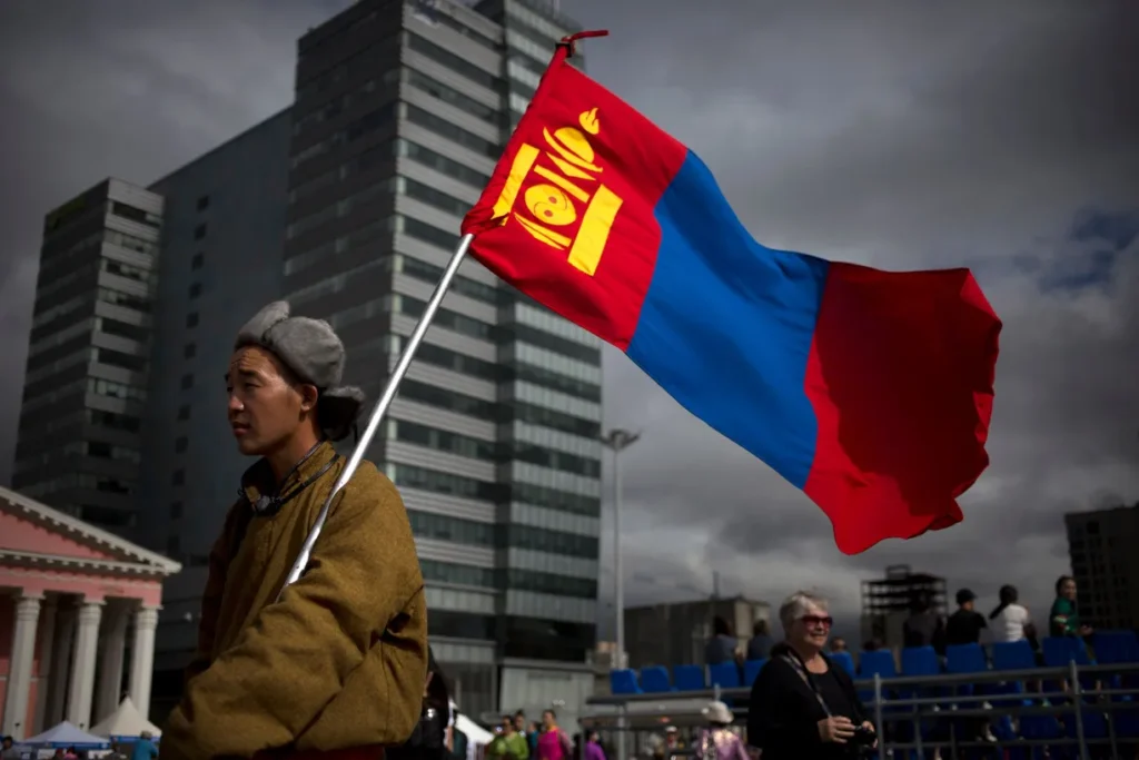 A man holds a Mongolian flag as he walks across Sukhbaatar Square in the capital city, Ulaanbaatar, in 2016